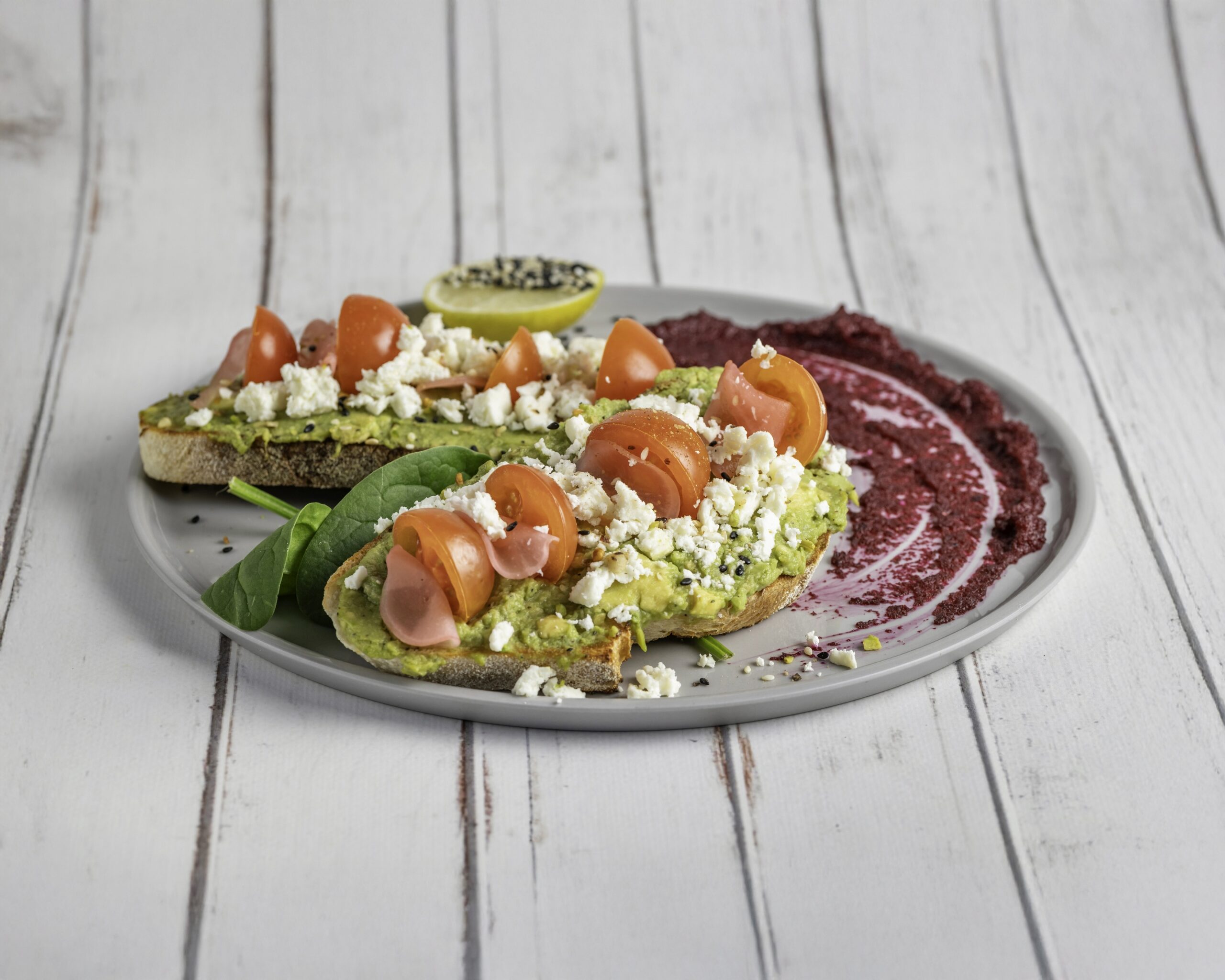 Smashed avocado with feta, tomatoes and pickled vegetables on sourdough